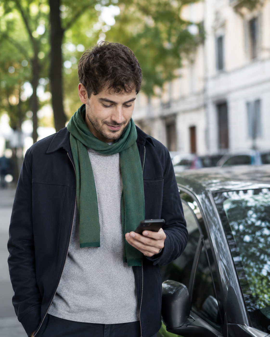 Cittadino usa lo smartphone vicino alla sua auto